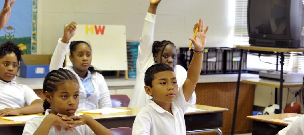 Students raise their hands to answer questions in a classroom